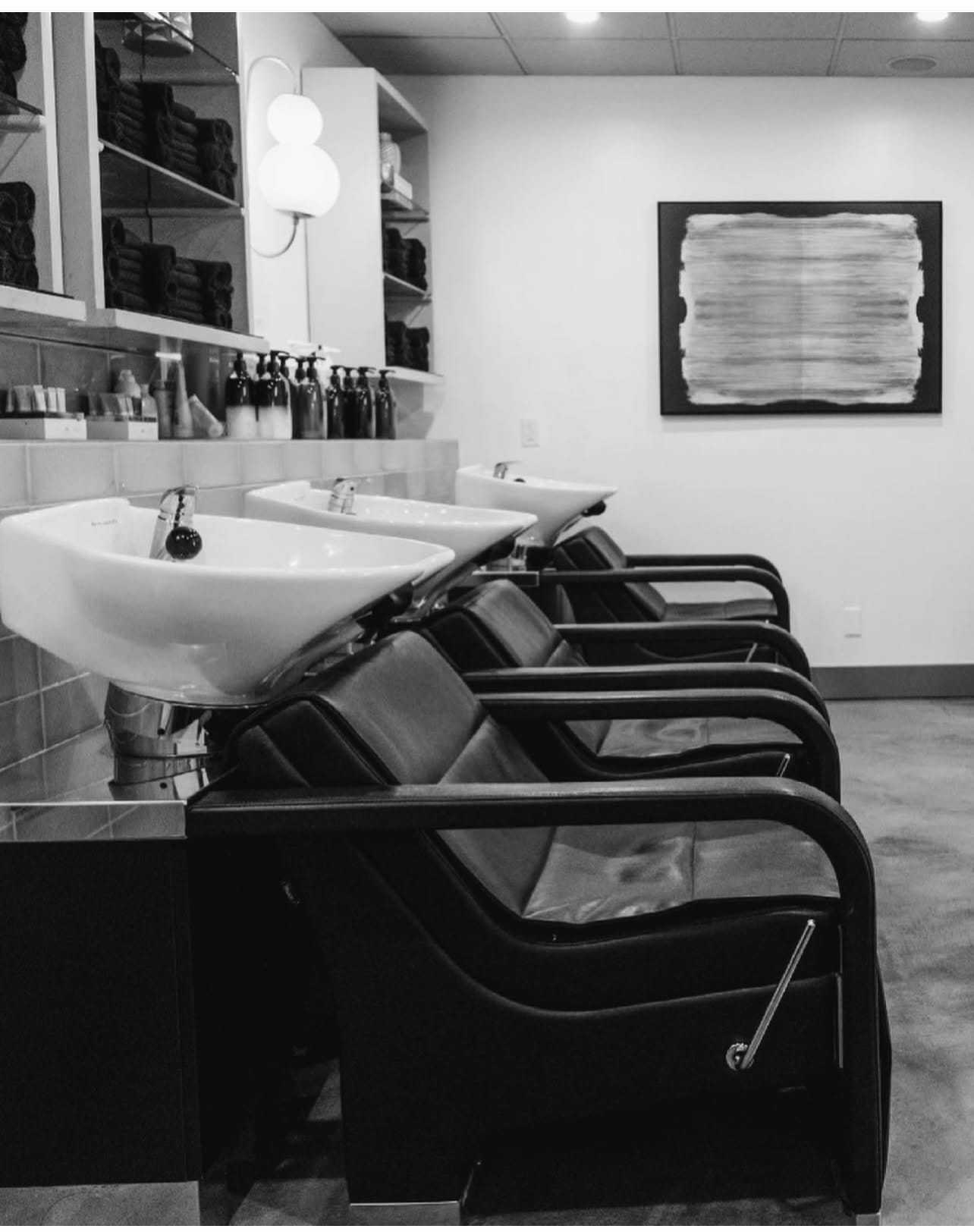 Salon shampoo stations with chairs and sinks, modern decor in black and white tones.