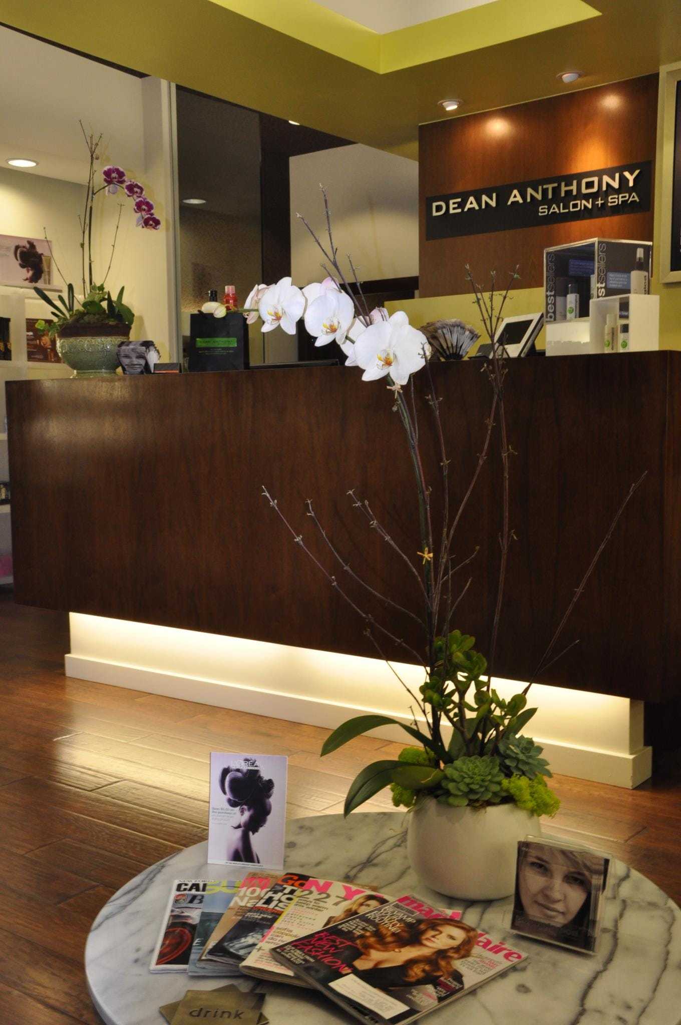 Salon reception with orchids and magazines on a marble table.