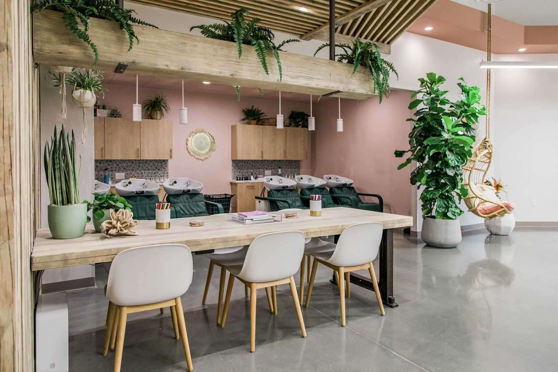 Modern salon with plants, a cozy seating area, and hair washing stations.