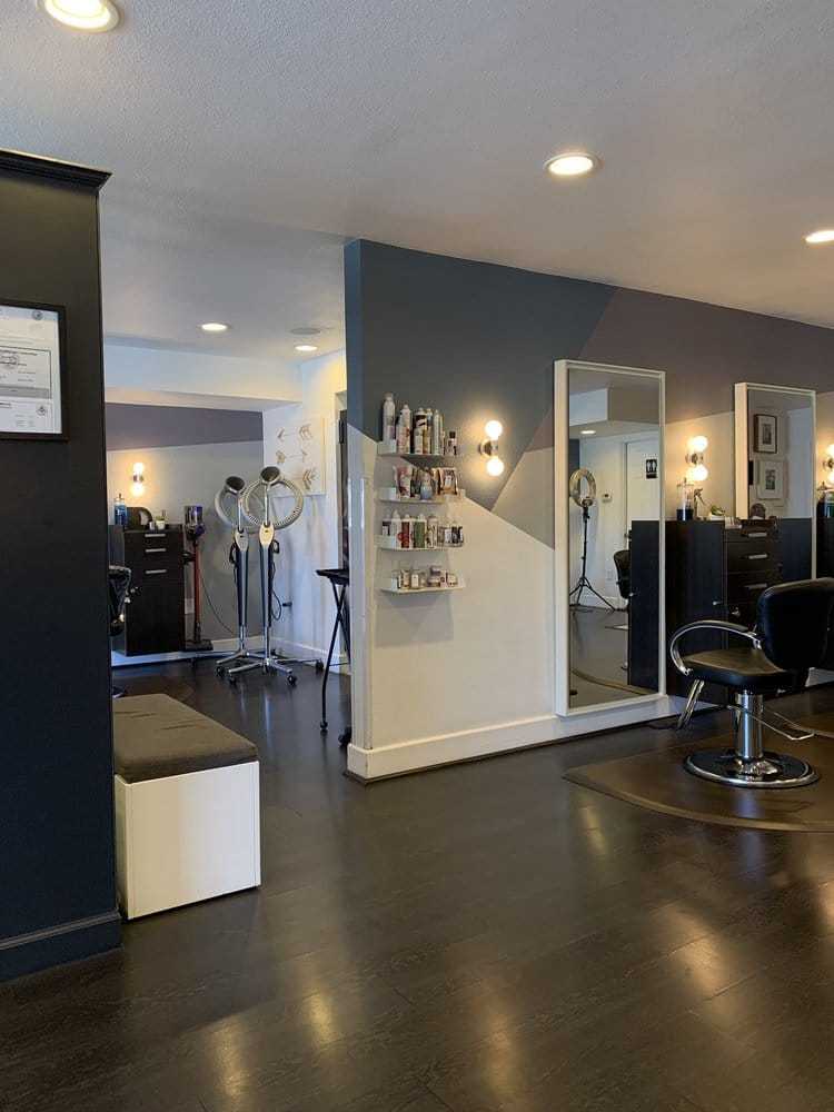 Modern hair salon interior with styling stations and hair products on shelves.
