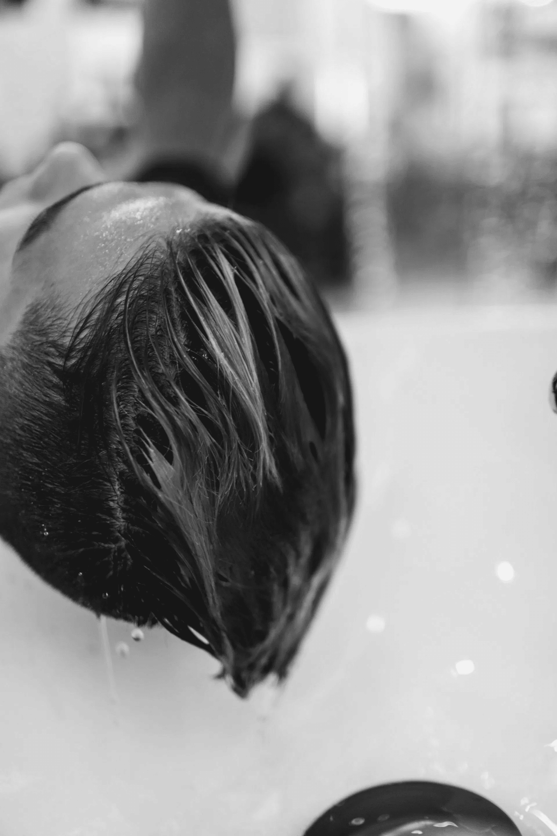 Person getting hair washed with blue dye in salon sink.
