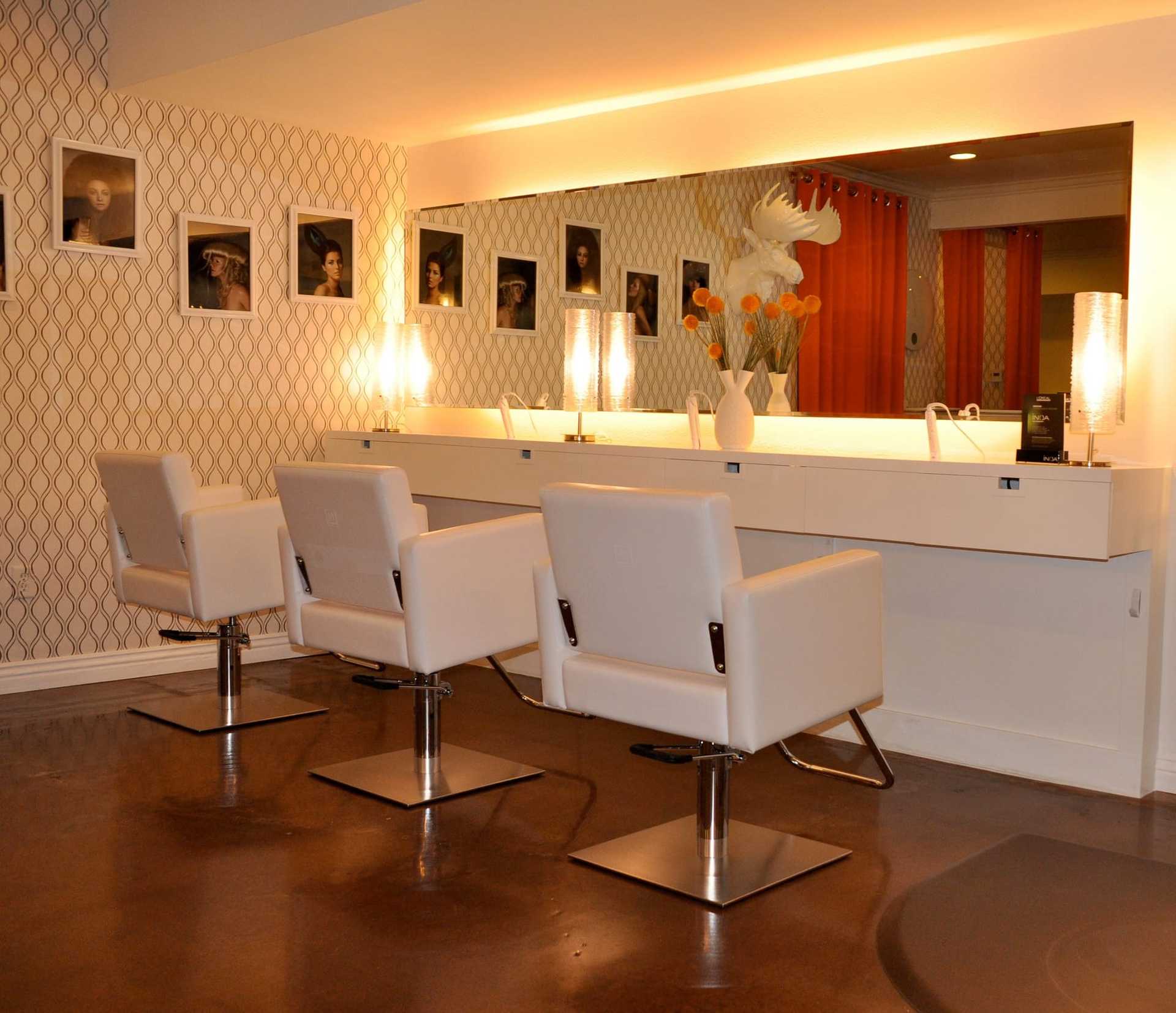 Stylish salon interior with three white chairs, mirrors, and modern lighting.
