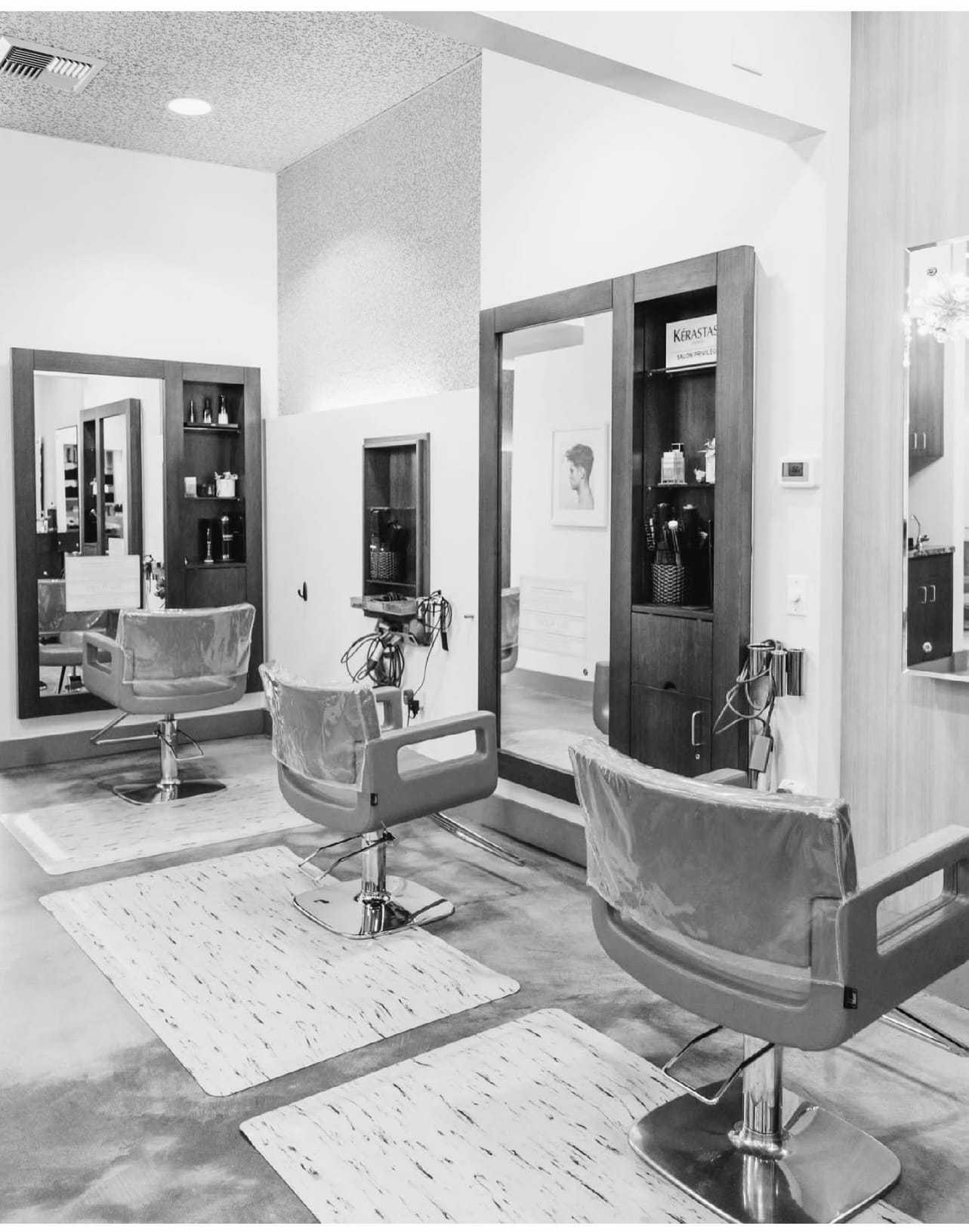 Salon interior with styling chairs, mirrors, and hair products on shelves.